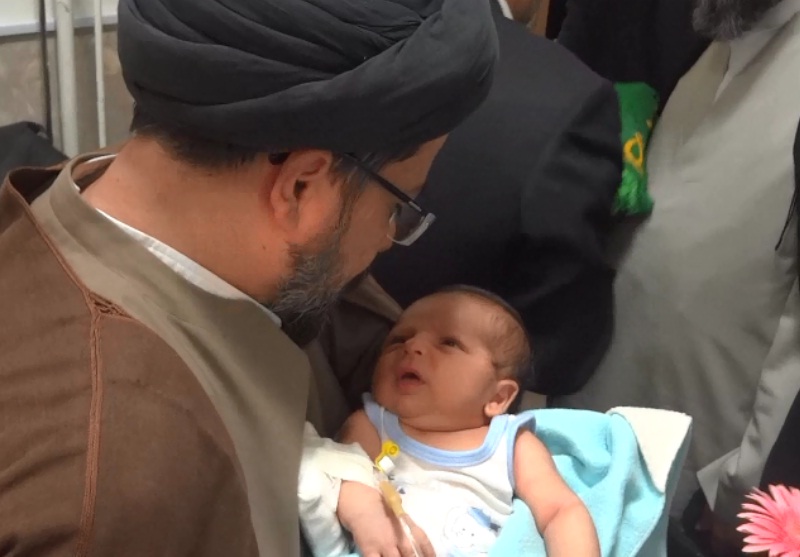 اذان خواندن حجت الاسلام علیزاده موسوی ، روحانی کاروان رضوی در گوش نوزاد صحنه ای